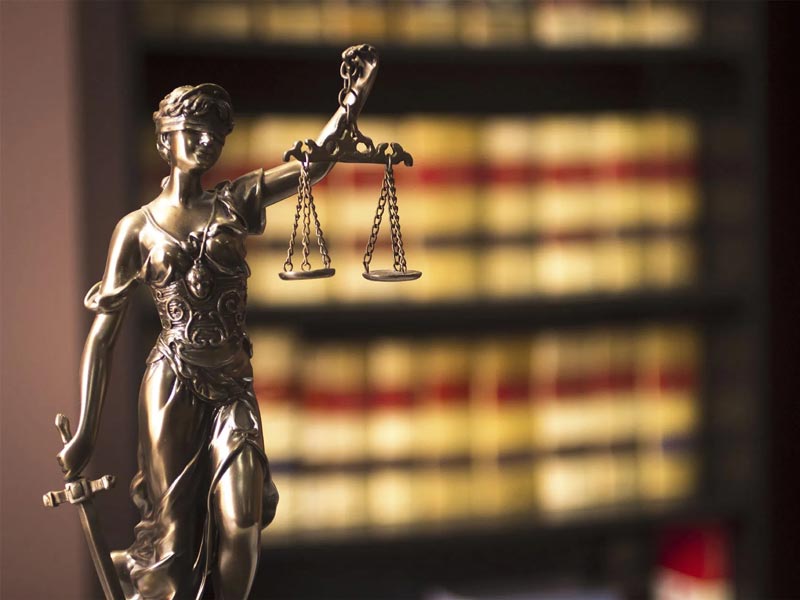 scales of justice statue with legal books in background